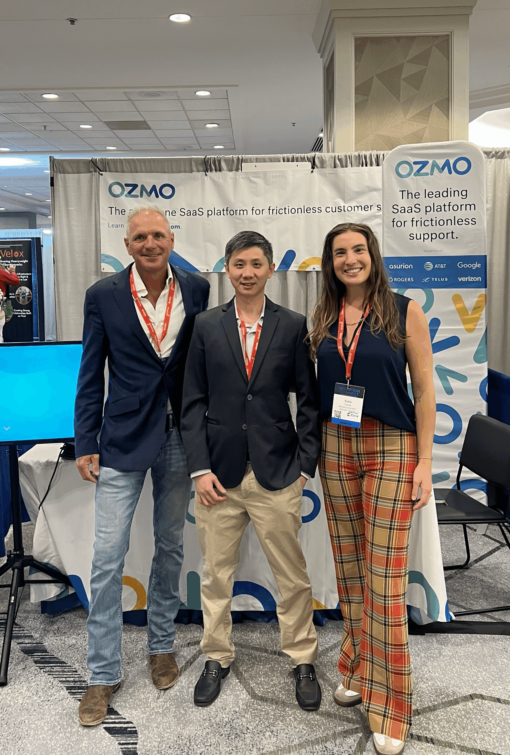 Ozmo's team of experts exhibiting at Mountain Connect 2025. Three individuals standing in front of Ozmo's tradeshow booth.